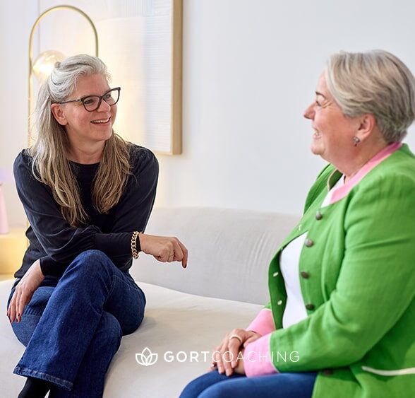 Coach führt einen ressourcenorientierten Dialog mit Klientin zur Stärkung beruflicher Resilienz.