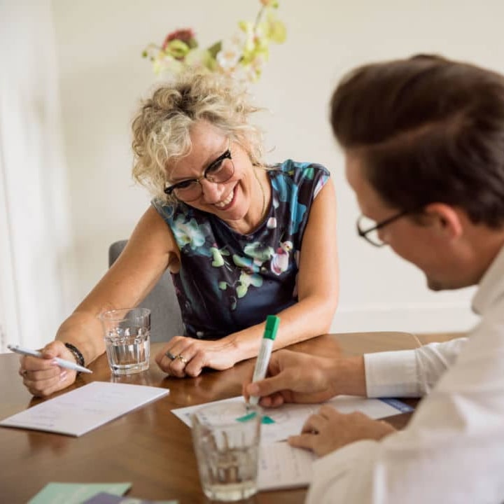 Female psychologist in conversation with young male coachee taking notes during life coaching
